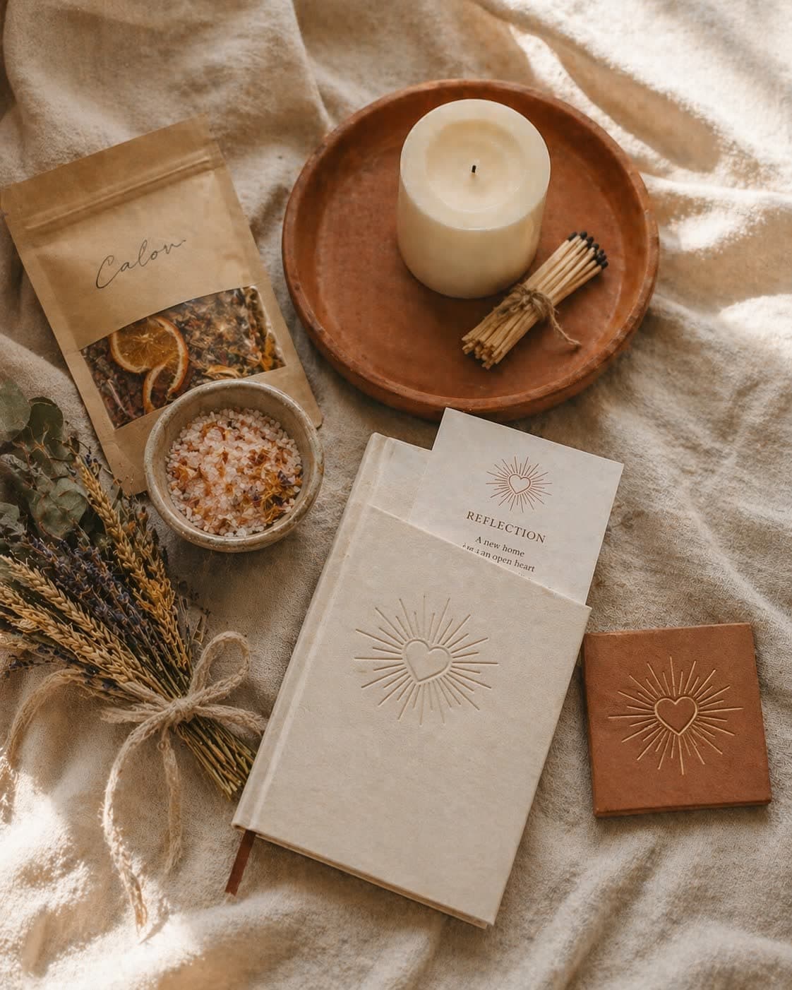 The Casa Box (New Home) — a warm editorial composition of the welcome-home gift box with Luz candle, Calor blessing salts, dried floral bundle, journal, and terracotta tile on linen.