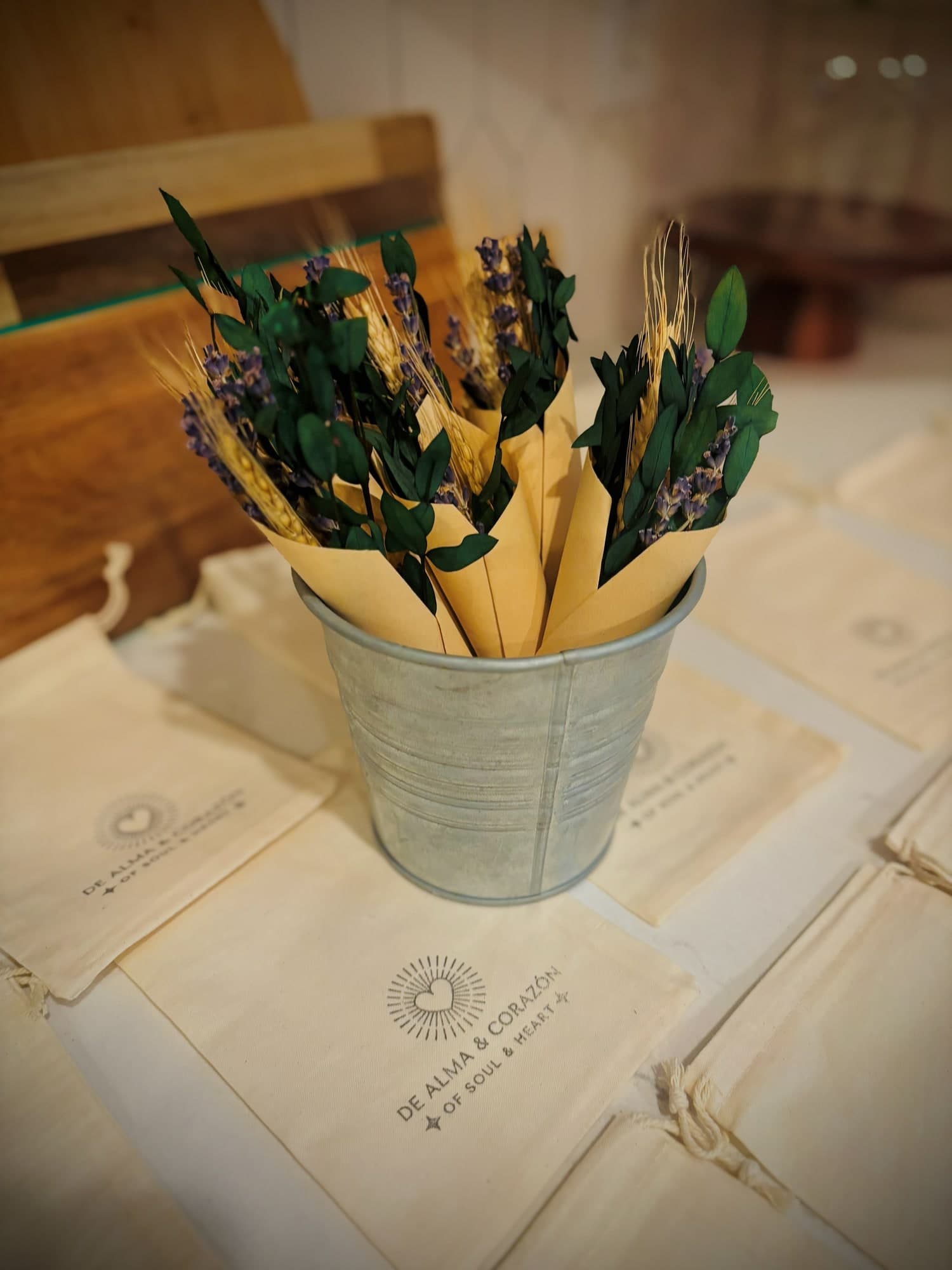 Small dried bouquets of lavender, wheat and greenery wrapped in paper cones, in a tin bucket