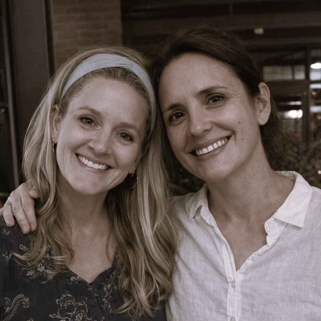 Olivia Garza Holub and Emily Murillo, the founders of De Alma y Corazón, side by side and smiling, one with an arm around the other's shoulder